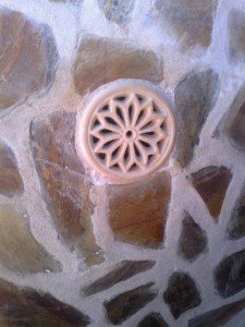  Rejilla redonda instalada sobre una superficie de pizarra y cemento.